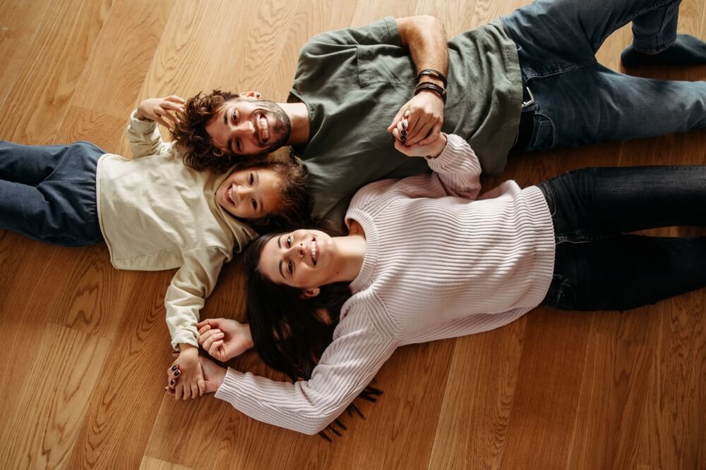 Happy family with a little girl lying on the hardwood floor